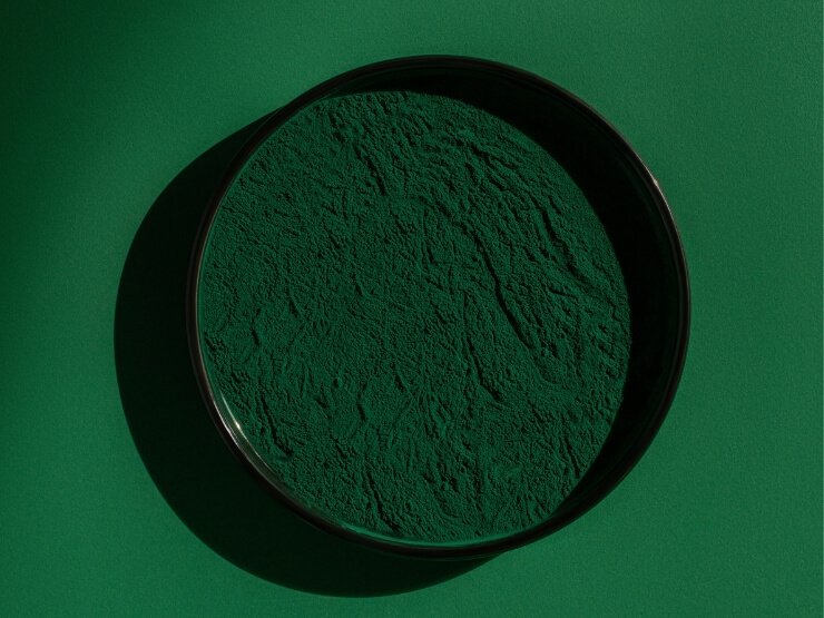 Polvere di alghe spirulina fresca su sfondo verde